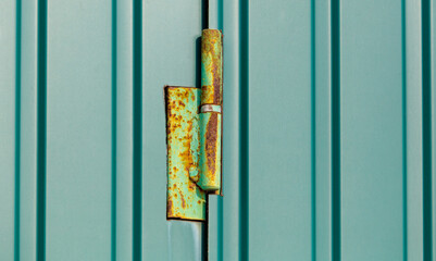 A green door hinge is rusted