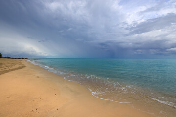 Fototapeta premium Beach with a cloudy sky in the background