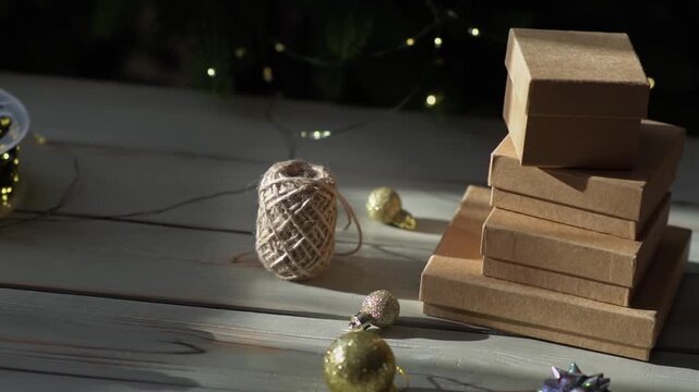 Holiday decor. Packing holiday gifts. Gift boxes, silver bow and Christmas gold balls against the backdrop of the Christmas tree and golden bokeh