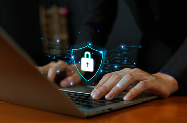 Businessman using laptop with digital shield and padlock icon, representing cybersecurity, data protection, privacy, encryption, and secure online network technology in modern digital business concept
