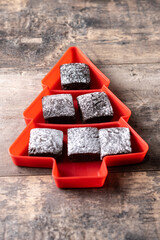 Chocolate brownies with powdered sugar in Christmas tree tray on wooden table