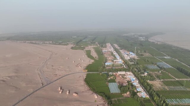 Aerial view of farms and desert landscape showing the contrast between the green fields and the arid terrain, Yangguan, Gansu, China.