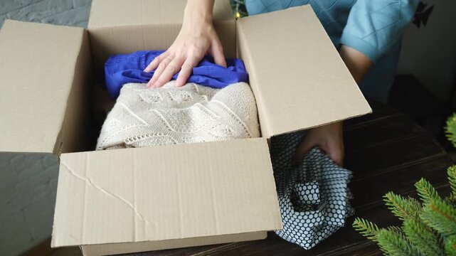 Christmas donation, charity concept. Woman contributes clothes for Christmas charitable donation