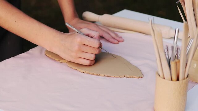 Pottery Cutting Clay Close-up 4k video. Cutting clay precise patterns using shaping tool during the early stages of ceramic artistry. Ceramic artist cuts designs into clay with steady precision.