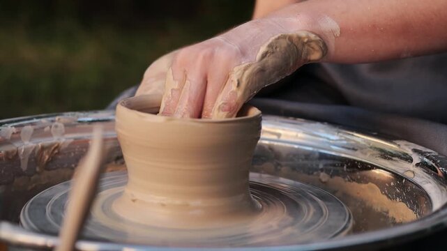 Clay is shaped on a spinning pottery wheel, creating the first form of a ceramic vessel 4k video. Hands centering clay on wheel. Clay is centered on a pottery wheel to ensure balance before shaping.