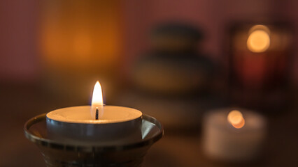 A candle in the foreground and other blurred decorative objects in the background. Candles lit at night. Spa decorative objects.