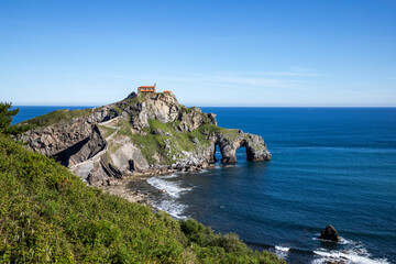 Dramatic coastal fortress perched on rocky island with ancient stone staircase leading to building overlooking vast ocean horizon