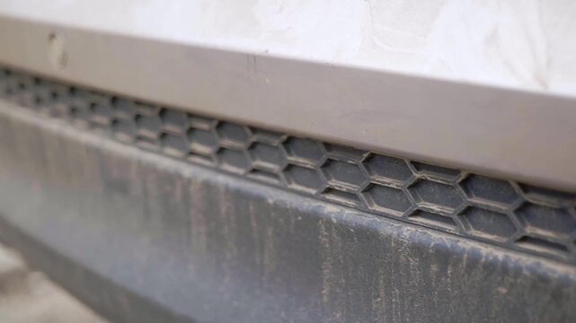 Super dirty and muddy rear bumper trime on SUV with hexagon pattern