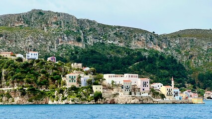 Kastellorizo Megisti, Greece: Ferry view of colorful houses, mountains, and sea in foreground. Summer vacation, Mediterranean travel, Greek island, coastal landscape, scenic seaside, summer holiday 