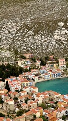 Vertical photo. Aerial view of the town on Kastellorizo (Megisti) Island, Greece. Greek island travel, Mediterranean vacation, scenic landscape, summer tourism, traditional houses, coastal scenery. 
