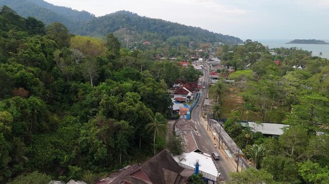 aerial flyover footage of Koh Chang island, Kai Bae village with roads and traffic with mountains and jungle