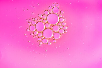 Macro photo of oil bubbles on a soft pink background. Transparent drops form delicate geometric shapes, radiating warmth, elegance, and dreamy aesthetics. Copy space