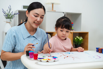happy mother and toddler girl painting watercolor in paper at home