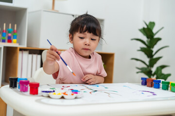 happy toddler girl painting watercolor in paper at home