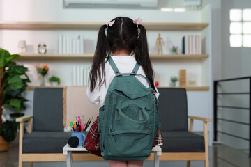 Back to School. Young girl with backpack facing away, ready for school in modern home.