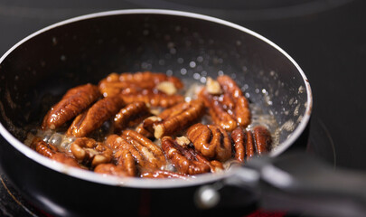 close up of pecan nuts being caramelized in a pan