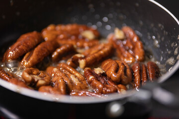close up of pecan nuts being caramelized in a pan