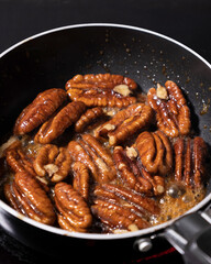close up of pecan nuts being caramelized in a pan
