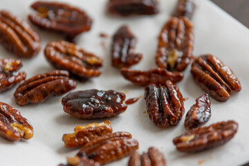caramelized pecans on white background close up
