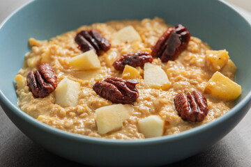 creamy pumpkin oatmeal topped with fresh apple slices and caramelized pecans