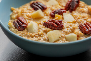 creamy pumpkin oatmeal topped with fresh apple slices and caramelized pecans