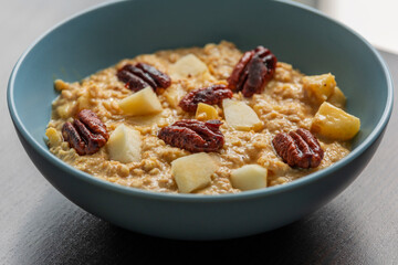 creamy pumpkin oatmeal topped with fresh apple slices and caramelized pecans