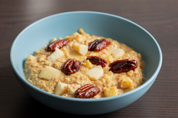 creamy pumpkin oatmeal topped with fresh apple slices and caramelized pecans