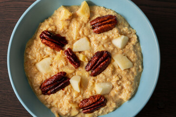 creamy pumpkin oatmeal topped with fresh apple slices and caramelized pecans