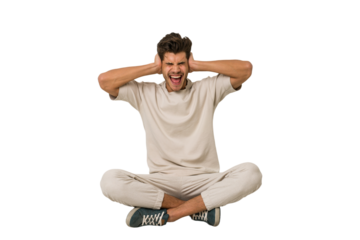 Young caucasian man sitting on the floor isolated on white background covering ears with hands trying not to hear too loud sound.