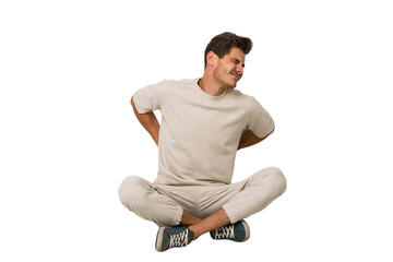 Young caucasian man sitting on the floor isolated on white background suffering a back pain.