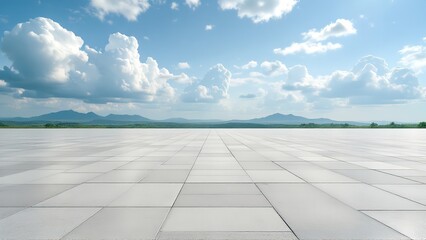 Expansive paved plaza with mountains and clouds in the distance under a blue sky