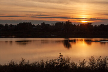 A serene sunset reflecting on a still lake surface.