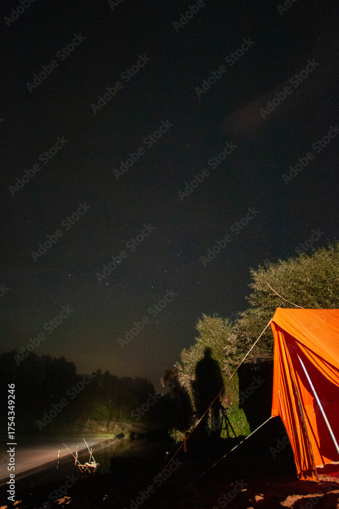 Canvas Prints a person is standing in front of an orange tent. the tent is set up in a forest