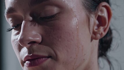 Extreme close up of a sweaty and emotional female dancer's face. A single tear rolls down her cheek from intense passion and exertion