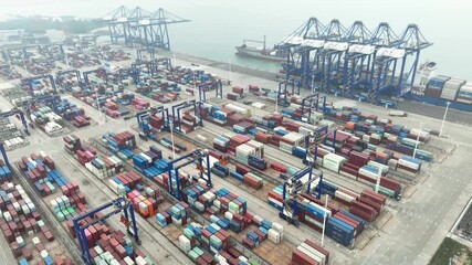 Xiamen, China - 17 September 2025: Aerial view of neatly stacked shipping containers creating a colorful grid at the bustling port with towering cranes.