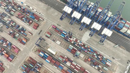 Xiamen, China - 17 September 2025: Aerial view of a vast port with colorful containers neatly stacked, awaiting transport by a large cargo ship and towering cranes.