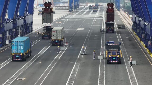 Xiamen, China - 17 September 2025: Aerial view of container trucks being loaded with colorful cargo containers at a bustling shipping yard.