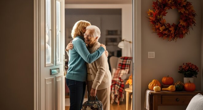 Two happy women hugging at home doorway. Senior mother with adult daughter reuniting in autumn