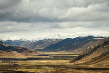Tibet aerial view Expansive landscape of the Tibetan Plateau with snow-capped mountains and arid valleys under dramatic skies. Remote wilderness at the roof of the world 
