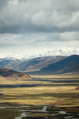Tibet aerial view Expansive landscape of the Tibetan Plateau with snow-capped mountains and arid valleys under dramatic skies. Remote wilderness at the roof of the world 