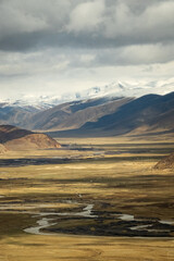 Tibet aerial view Expansive landscape of the Tibetan Plateau with snow-capped mountains and arid valleys under dramatic skies. Remote wilderness at the roof of the world 