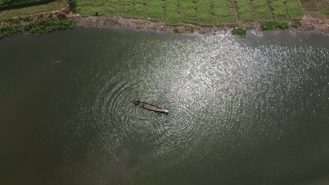Makurdi, Nigeria - 13 October 2025: Aerial view of a small boat sailing serenely on the shimmering, sun-kissed waters of the Benue River, a tranquil scene.