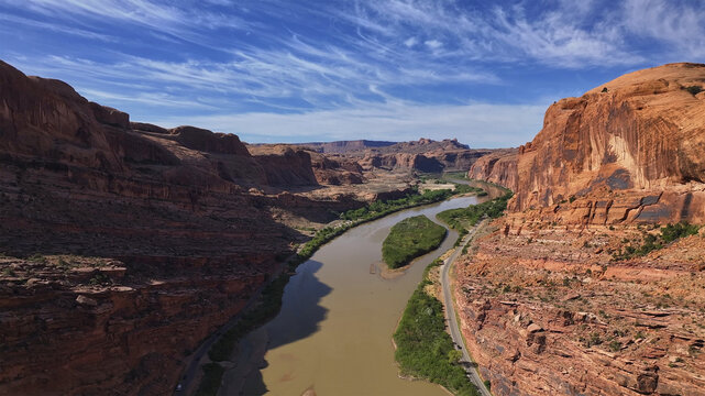 Aerial view of the muddy river winding through the red rock canyons under a vast sky, Moab, Utah, United States.