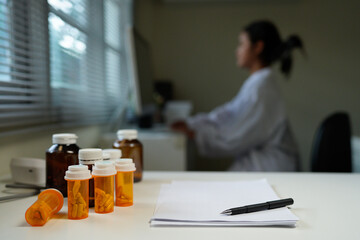 Blank Paper with Pen and A Bottle of medicine pills on Table at office room