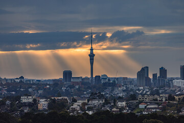 ニュージーランド　オークランドのマウント・ウェリントンから見えるスカイタワーと夕焼け空にかかる光芒