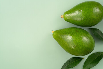Fresh avocado with sliced and diced pieces over green table background.