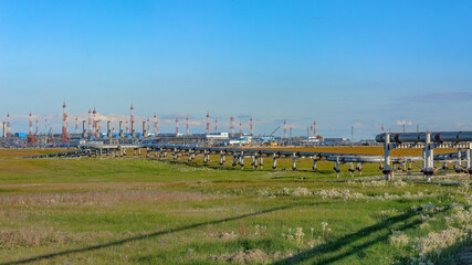 In the foreground is a gas pipeline in the summer tundra at the severnoye field. In the background...