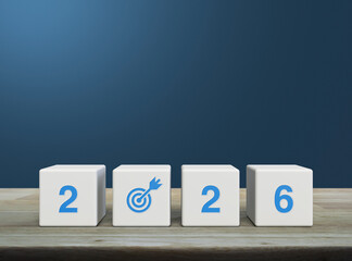2026 letter with goal icon on white block cubes on wooden table over light blue wall, Happy new year 2026 success concept