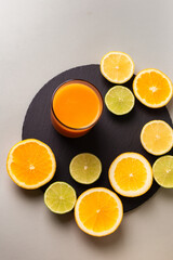 Glasse of healthy smoothie and citrus fruits - lemon, orange, lime on black stone desk on grey background. A glass of smoothie made from mango, peach, apricot.