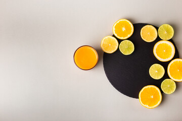 Glasse of healthy smoothie and citrus fruits - lemon, orange, lime on black stone desk on grey background. A glass of smoothie made from mango, peach, apricot.